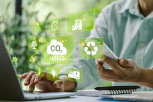 Person mit Laptop und Smartphone in der Hand. Symbole für CO2-Einsparung